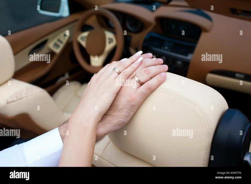 Руки с обручальными кольцами в машине