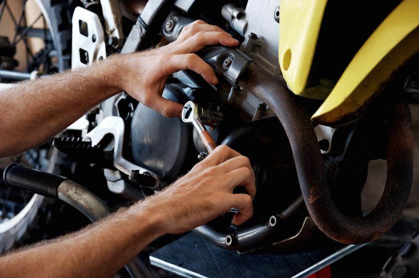 Ремонтирует мотоцикл