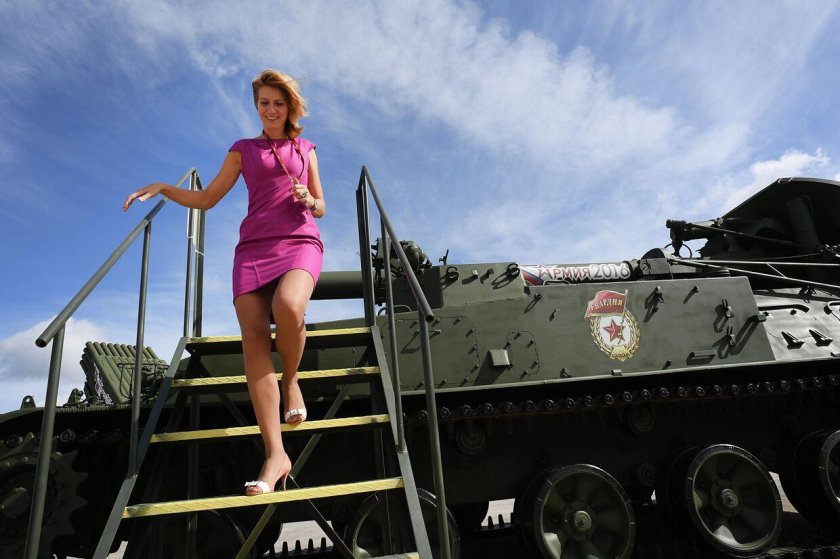 Девушки на фоне военной техники