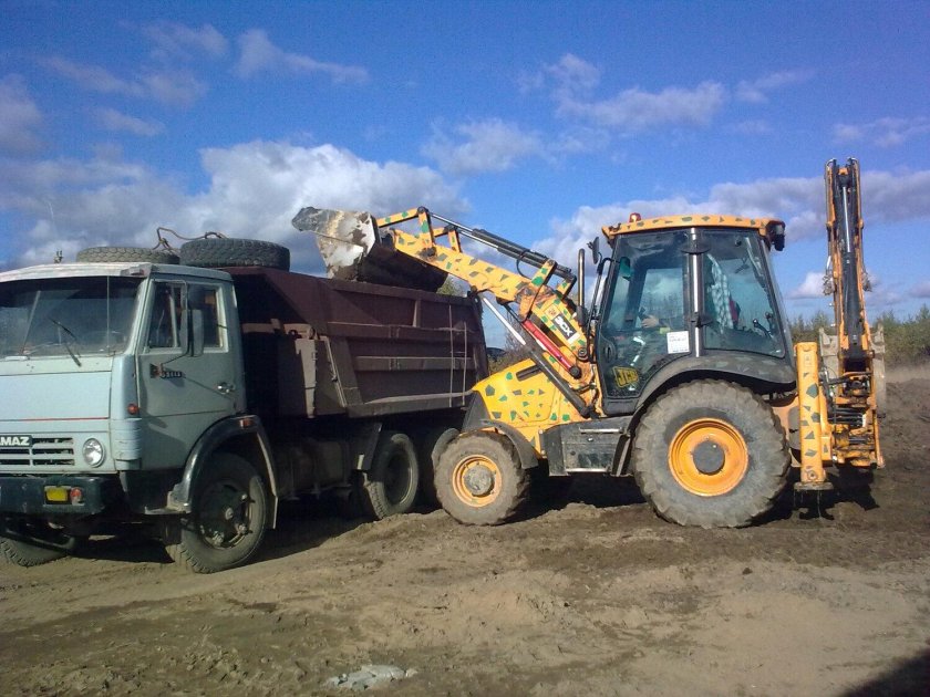 Экскаватор грузит песок в КАМАЗ