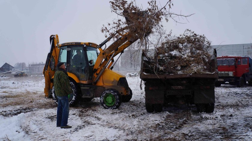КАМАЗ грузит трактор мусором