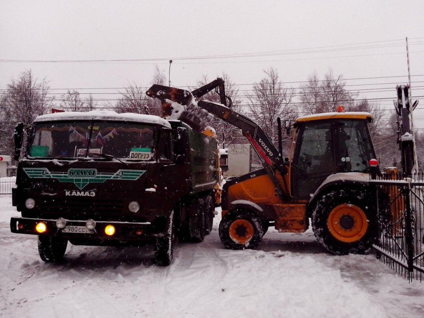 Экскаватор погрузчик грузит снег