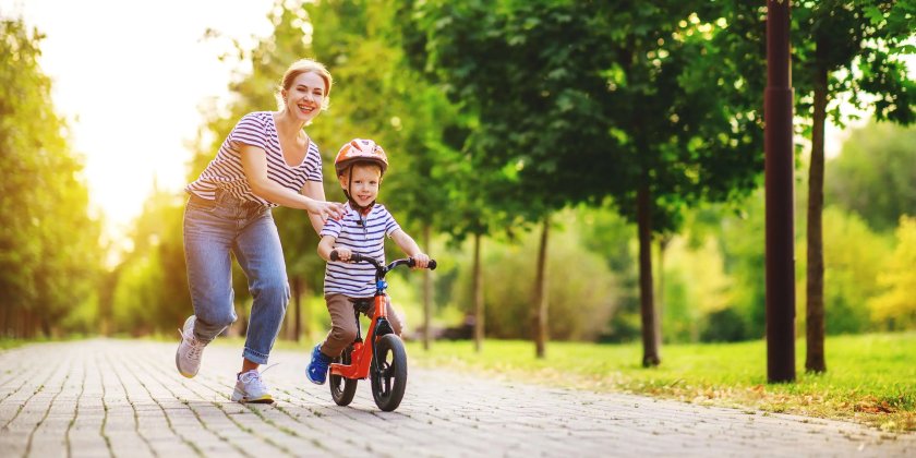 Мама учит ребенка кататься на велосипеде