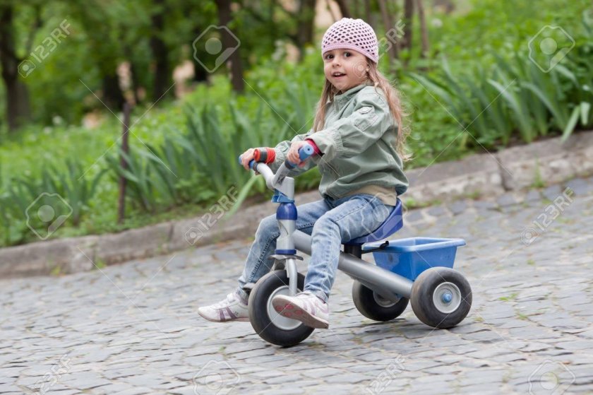 Девочка на маленькая на трехколёсном велосипеде